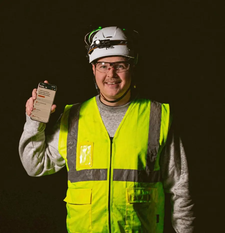 Julius Anttila työmaalla kypärä päässä ja Tendy puhelimen näytöllä